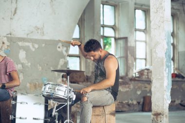 Rock müzik grubu tekrarı. Elektro gitar çalar ve davulcu arkasında davul seti.