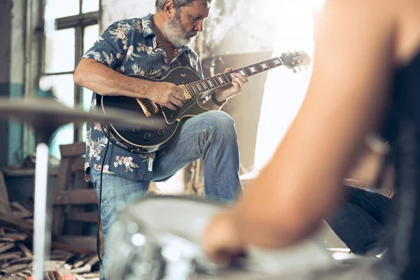 Repetition of rock music band. Electric guitar player and drummer behind the drum set.