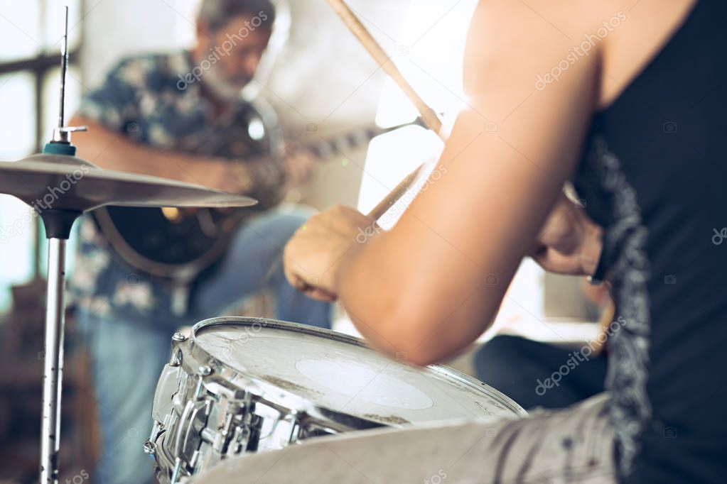 Repetition of rock music band. Electric guitar player and drummer behind the drum set.