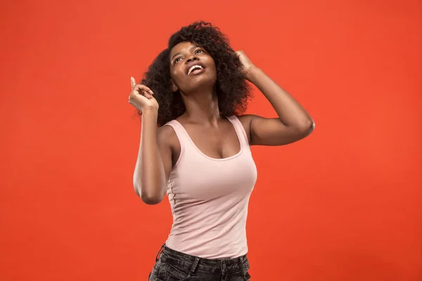 La mujer africana feliz de pie y sonriendo sobre el fondo rojo . —  Fotos de Stock