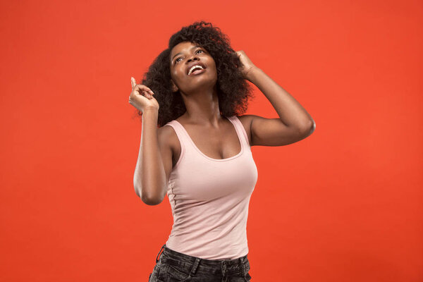 Happy business woman standing and smiling isolated on red studio background. Beautiful female half-length portrait. Young emotional afro woman. The human emotions, facial expression concept. Front