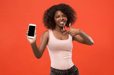 Boş ekran cep telefonu izole kırmızı arka plan üzerinde gösterilen emin casual afro kız portresi