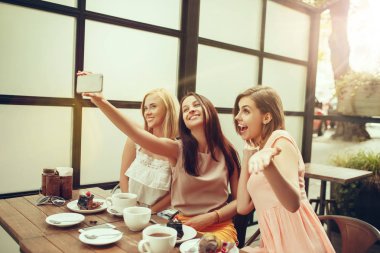 İki kız arkadaş birlikte vakit geçirmek kahvaltı ve tatlı olan kafede kahve içme.