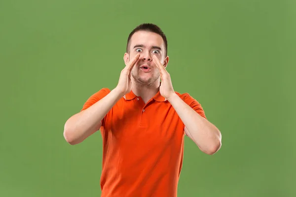 Isolated on green young casual man shouting at studio — Stock Photo, Image