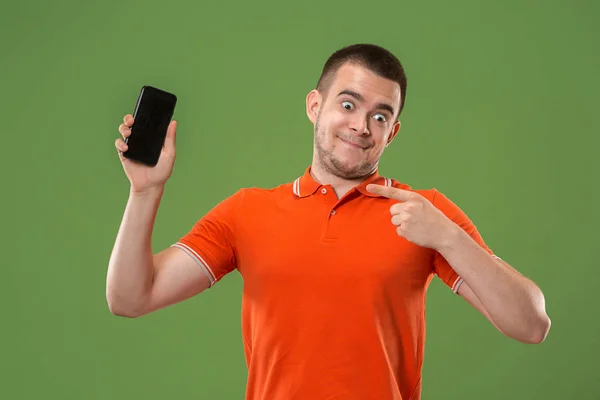 Ο ευτυχισμένος άνθρωπος που δείχνει στο κενή οθόνη του κινητού τηλεφώνου ενάντια σε πράσινο φόντο. — Φωτογραφία Αρχείου