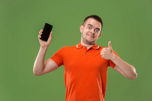 Ο ευτυχισμένος άνθρωπος που δείχνει στο κενή οθόνη του κινητού τηλεφώνου ενάντια σε πράσινο φόντο. — Φωτογραφία Αρχείου