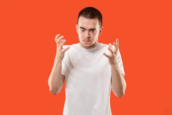 De emotionele boos jongeman op oranje studio achtergrond — Stockfoto