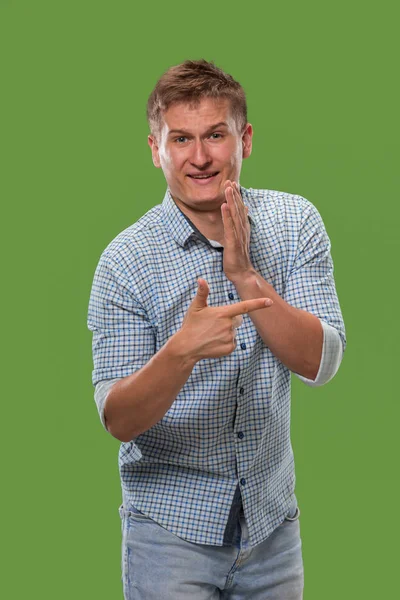 The young man whispering a secret behind her hand over green background — Stock Photo, Image