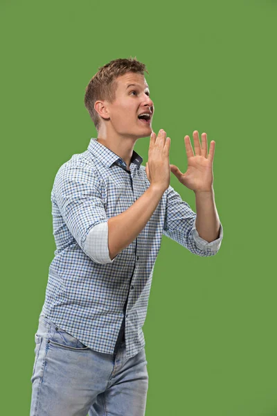 Isolated on green young casual man shouting at studio — Stock Photo, Image