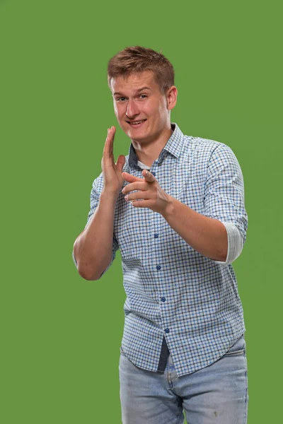 Der junge Mann flüstert ein Geheimnis hinter ihrer Hand vor grünem Hintergrund — Stockfoto