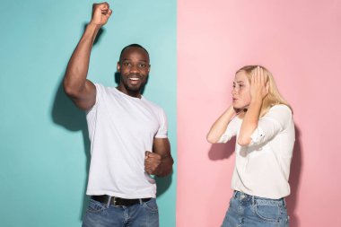 Biz kazandık. Kazanan başarı mutlu afro erkek ve kadın bir kazanan olmak kutluyor. Beyaz kadın ve erkek model pembe studio üzerinde dinamik görüntü.