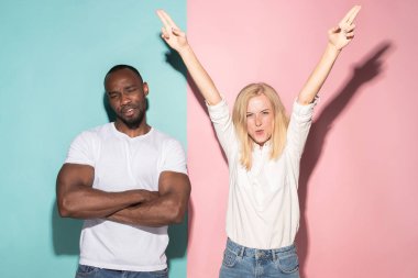 Biz kazandık. Kazanan başarı mutlu afro erkek ve kadın bir kazanan olmak kutluyor. Beyaz kadın ve erkek model pembe studio üzerinde dinamik görüntü.