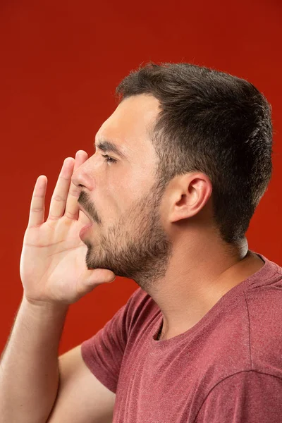 Isolado no vermelho jovem casual gritando no estúdio — Fotografia de Stock