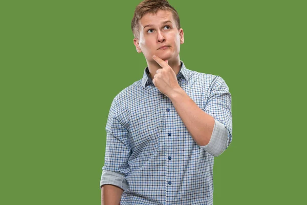 Let me think. Doubtful pensive man with thoughtful expression making choice against green background — Stock Photo, Image