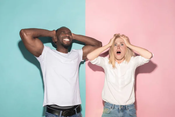 Ganamos. Ganar el éxito feliz afro hombre y mujer celebrando ser un ganador. Imagen dinámica del modelo femenino y masculino caucásico en el estudio rosa . —  Fotos de Stock