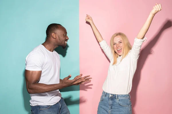 Ganhámos. Ganhando sucesso feliz afro homem e mulher celebrando ser um vencedor. Imagem dinâmica do modelo feminino e masculino caucasiano no estúdio rosa . — Fotografia de Stock