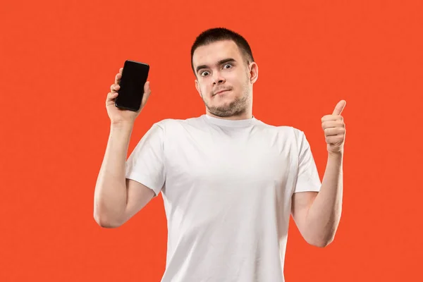 Ο ευτυχισμένος άνθρωπος που δείχνει στο κενή οθόνη του κινητού τηλεφώνου ενάντια σε πορτοκαλί φόντο. — Φωτογραφία Αρχείου
