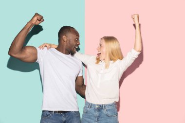 Biz kazandık. Kazanan başarı mutlu afro erkek ve kadın bir kazanan olmak kutluyor. Beyaz kadın ve erkek model pembe studio üzerinde dinamik görüntü. Zafer, zevk kavramı. İnsan yüz duyguları kavramı.