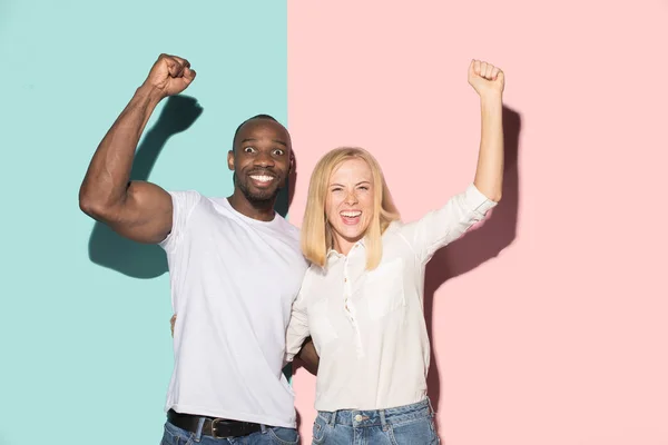 Vi vann. Vinnande framgång lycklig afro man och kvinna som firar att vara en vinnare. Dynamisk bild av kaukasiska kvinnliga och manliga modell på rosa studio. — Stockfoto