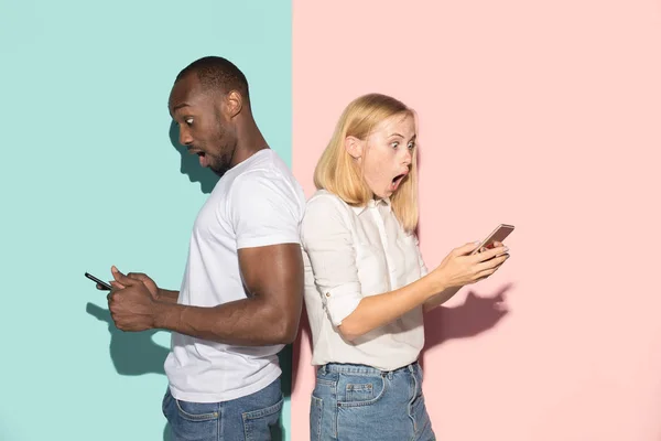 Ein gemischtes Studentenpaar nahm Mobiltelefone an sich. Kaukasisches Mädchen und ihr afrikanischer Freund posieren im Studio . — Stockfoto