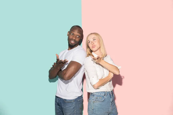 Beau portrait féminin et masculin sur fond studio rose et bleu. Le jeune couple émotionnel — Photo