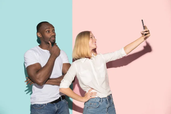 Mixte couple d'étudiants prenant selfie commun avec téléphone. caucasienne fille et son africain copain posant à studio  . — Photo