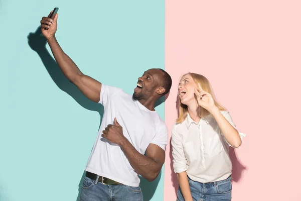 Mixed raced couple of students taking common selfie with phone. Caucasian girl and her African boyfriend posing at studio . — Stock Photo, Image