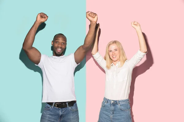 Vi vann. Vinnande framgång lycklig afro man och kvinna som firar att vara en vinnare. Dynamisk bild av kaukasiska kvinnliga och manliga modell på rosa studio. — Stockfoto