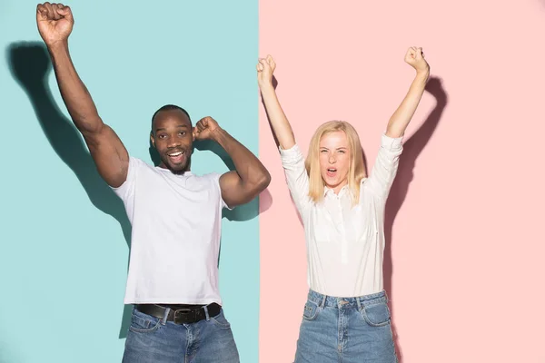 Ganamos. Ganar el éxito feliz afro hombre y mujer celebrando ser un ganador. Imagen dinámica del modelo femenino y masculino caucásico en el estudio rosa . —  Fotos de Stock