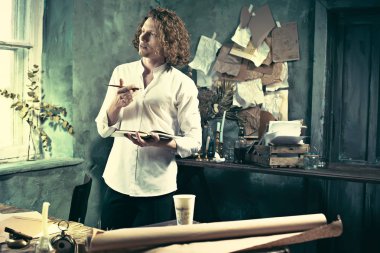 Yazar iş başında. Masanın ayakta ve zihninde bir şey yapma yakışıklı genç yazar