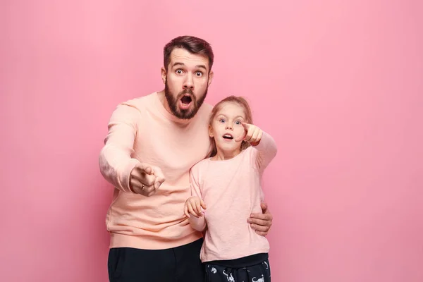 Surpreendido jovem família olhando para a câmera em rosa — Fotografia de Stock