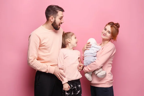 Förvånad ung familj tittar på kameran på rosa — Stockfoto