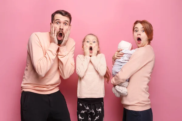 Surprised young family looking at camera on pink — Stock Photo, Image