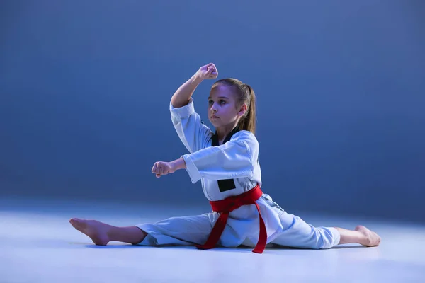 Chica joven entrenando karate sobre fondo azul — Foto de Stock
