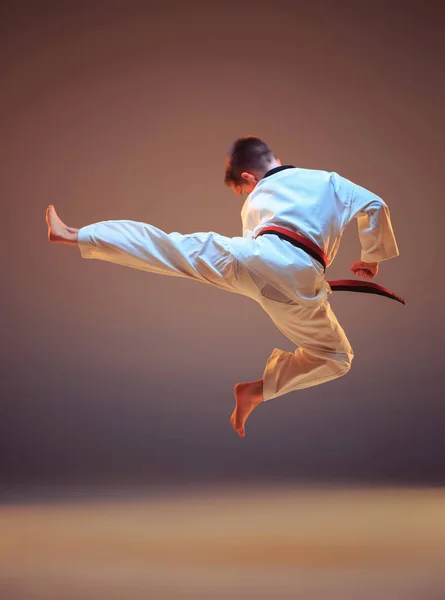 Jonge jongen opleiding karate op blauwe achtergrond — Stockfoto