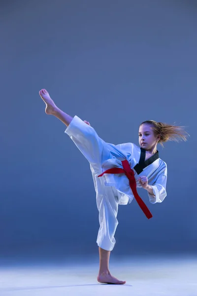 Jong meisje opleiding karate op blauwe achtergrond — Stockfoto