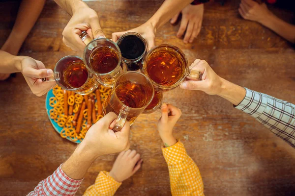 Mensen, vrije tijd, vriendschap en communicatie concept - happy vrienden drinken bier, praten en rammelende brillen bij bar of pub — Stockfoto