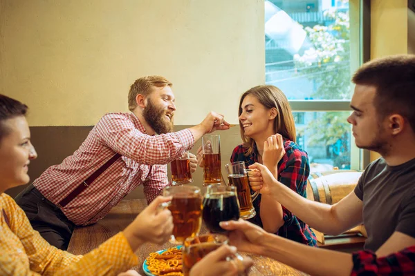 Persone, svago, amicizia e comunicazione concetto amici felici bere birra, parlare e bicchieri di clinking al bar o pub — Foto Stock