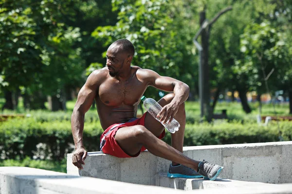 Sportler rastet aus und trinkt Wasser nach den Übungen im Stadion — Stockfoto