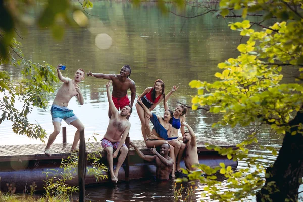 Korzystających ze stron rzeki z przyjaciółmi. Grupa piękny szczęśliwy młodych ludzi nad rzeką razem — Zdjęcie stockowe