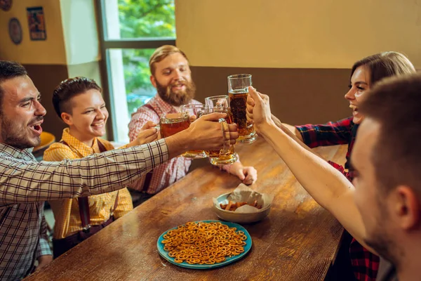 Menschen, Freizeit, Freundschaft und Kommunikationskonzept - glückliche Freunde trinken Bier, reden und klirren an der Bar oder Kneipe — Stockfoto