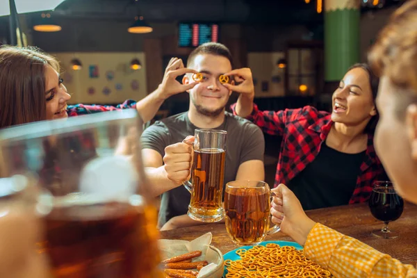 Mensen, vrije tijd, vriendschap en communicatie concept - happy vrienden drinken bier, praten en rammelende brillen bij bar of pub — Stockfoto