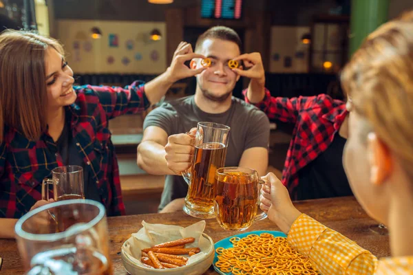 Mensen, vrije tijd, vriendschap en communicatie concept - happy vrienden drinken bier, praten en rammelende brillen bij bar of pub — Stockfoto