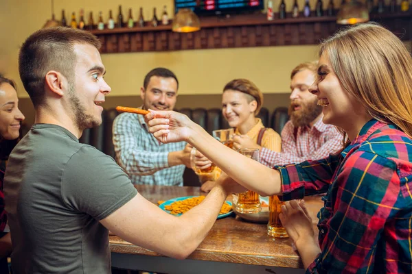 Mensen, vrije tijd, vriendschap en communicatie concept - happy vrienden drinken bier, praten en rammelende brillen bij bar of pub — Stockfoto