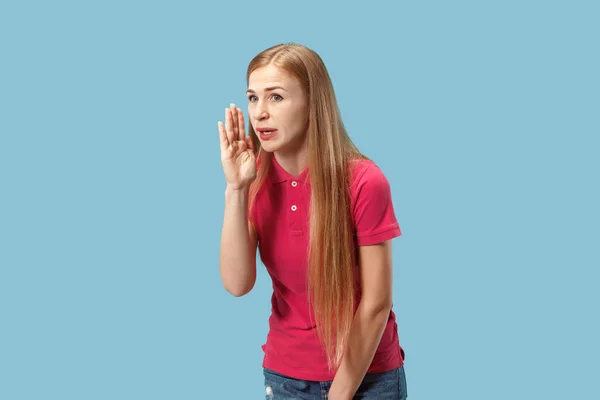 年轻女子在她的手背后耳语一个秘密蓝色背景 — 图库照片