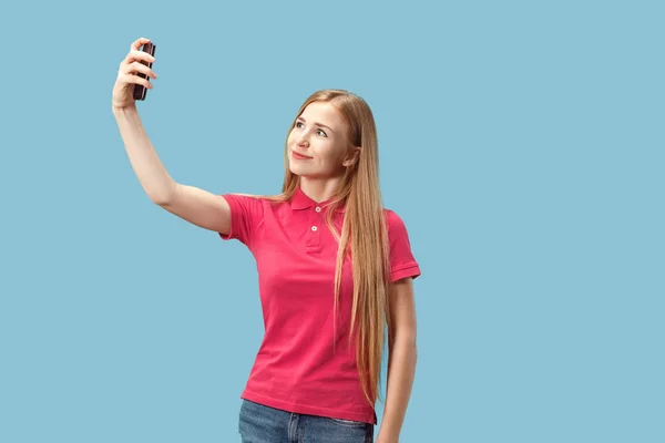 Portrét usmívající se příležitostné šťast zobrazuje prázdná obrazovka mobilní telefon nad modrým pozadím, samostatný — Stock fotografie