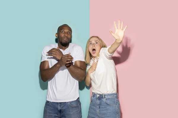 Retrato de la pareja asustada sobre fondo de estudio rosa y azul —  Fotos de Stock