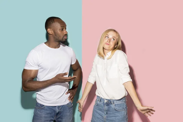 Hermoso retrato femenino y masculino sobre fondo de estudio rosa y azul. La joven pareja emocional —  Fotos de Stock