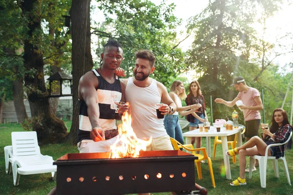 Grupo de amigos haciendo barbacoa en el patio trasero. concepto sobre el buen humor y positivo con los amigos — Foto de Stock