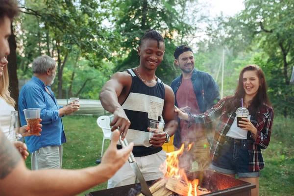 Un gruppo di amici che fanno barbecue in giardino. concetto di buon umore e positivo con gli amici — Foto Stock